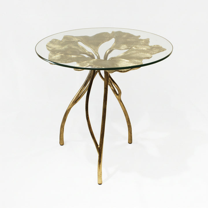 A round glass side table with a golden leaf design and three branch-like legs.